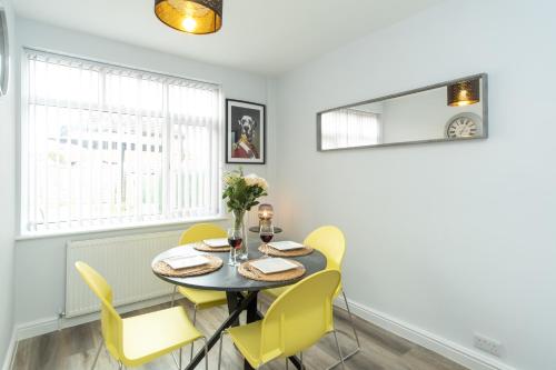 a dining room with a table and yellow chairs at Heath House in Burton upon Trent