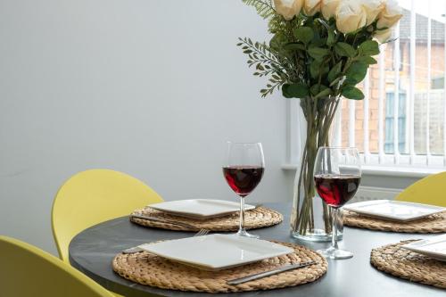 a table with a vase of roses and two glasses of wine at Heath House in Burton upon Trent
