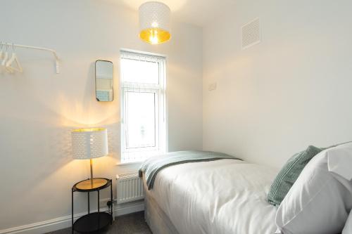 a white bedroom with a bed and a window at Heath House in Burton upon Trent