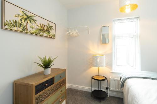 a bedroom with a bed and a dresser and a lamp at Heath House in Burton upon Trent
