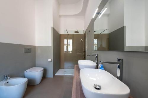 a bathroom with two sinks and a toilet and a mirror at Torino Station Relais in Turin