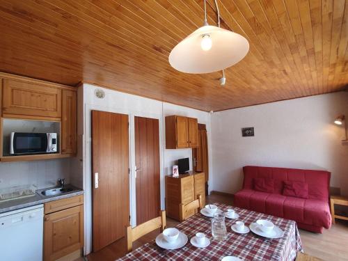une petite cuisine avec une table et un canapé rouge dans l'établissement Le Coolidge - BB2 - Studio centre - 4 pers, à Les Deux Alpes