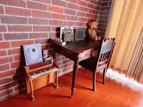 un escritorio con un oso de peluche y una silla junto a una pared de ladrillo en 猫とピアノと星空のリゾートブティックコテージ - Starry Forest Cottage Okinawa -, en Onna