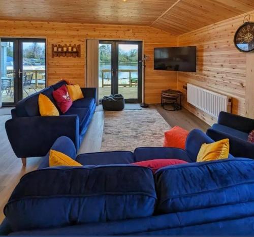 een woonkamer met blauwe banken en een flatscreen-tv bij Ferry Lodge in Brundall