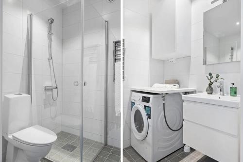 a bathroom with a washing machine and a toilet at Cozy apartment 2 stops-15 mins away from city center in Stockholm