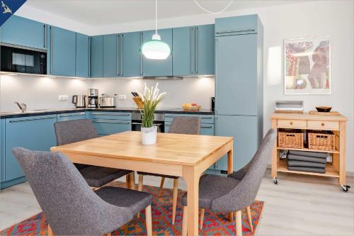 uma cozinha com armários azuis e uma mesa e cadeiras de madeira em Haffblick 1 em Zirchow