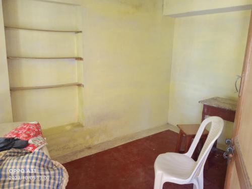 um quarto com uma cadeira, uma mesa e uma prateleira em Shanthi Illam em Madurai