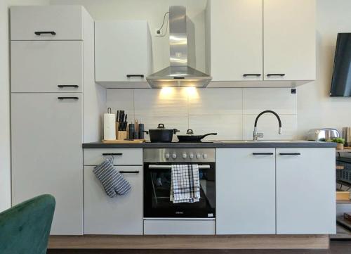 a kitchen with white cabinets and a stove top oven at Altstadt-oase in Cottbus
