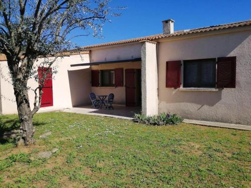 une maison avec une table et une chaise dans une cour dans l'établissement Maison près de la plage, à Penta-di-Casinca