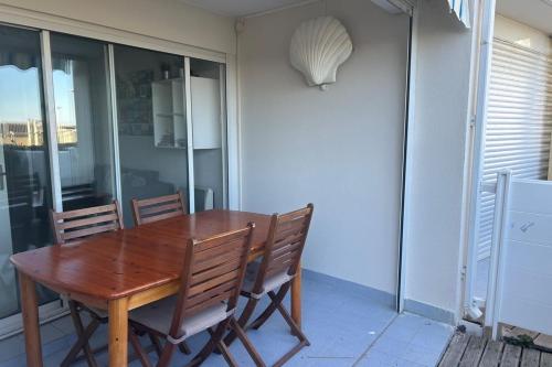 une table et des chaises en bois assises sur une terrasse dans l'établissement Apartment in Residence with Swimming Pool and direct beach access, à Frontignan