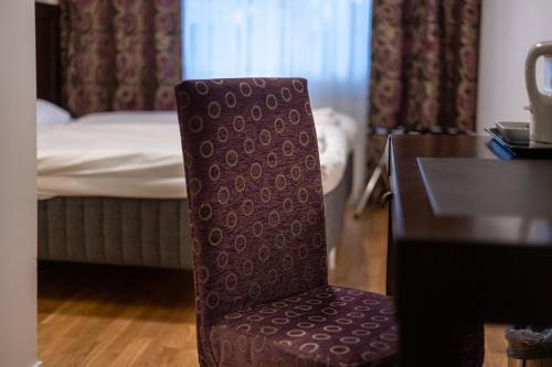 a chair in a room with a desk and a bed at Solna Park & Hotel in Solna