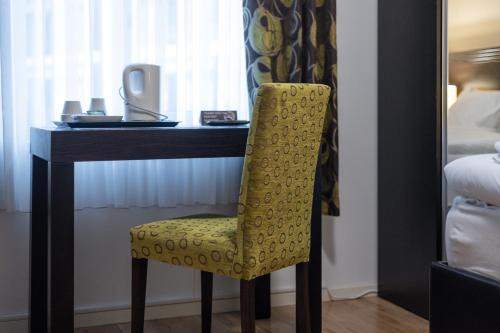 a yellow chair sitting at a desk in a hotel room at Solna Park & Hotel in Solna