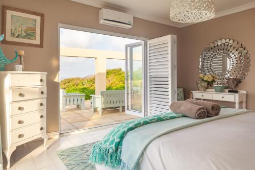 a bedroom with a bed and a balcony at Sunrise on Stiebel Rocks in Umzumbe
