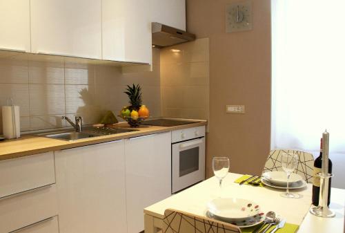 a kitchen with white cabinets and a table with wine glasses at Apartment Remy in Pula