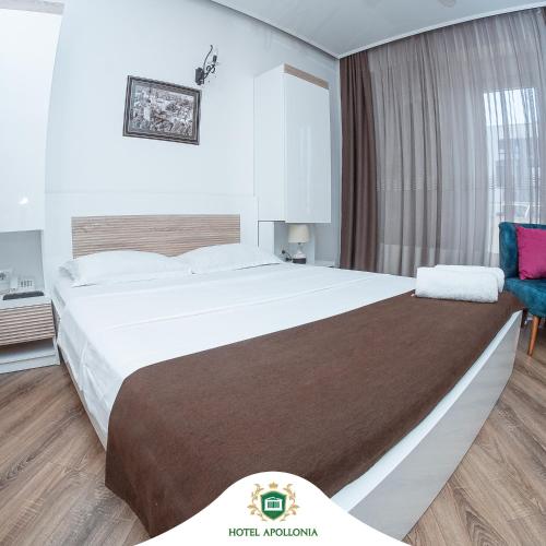 Hotel Apollonia في Gjakove: غرفة فندقية بسرير كبير وكرسي