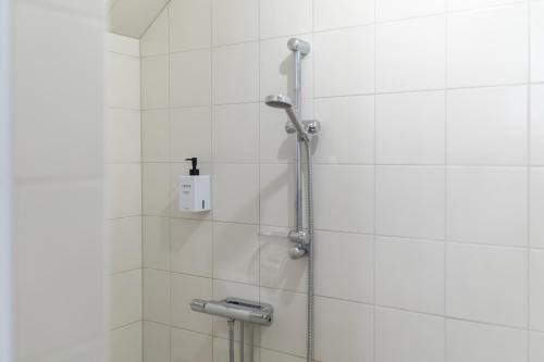 a shower in a bathroom with white tiles at Solna Park & Hotel in Solna