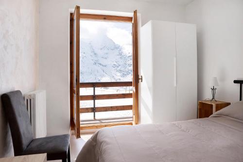1 dormitorio con ventana, 1 cama y 1 silla en Casa Rucas, en Bagnolo Piemonte