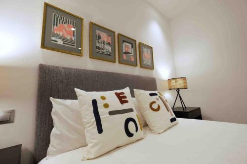 Un dormitorio con una cama blanca con algunas almohadas en CoLet Apartamento, en Sevilla