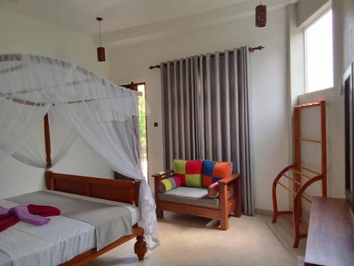 a bedroom with a bed and a chair and a window at LaRoy Mirissa-Introducing Smart Hotel in Mirissa
