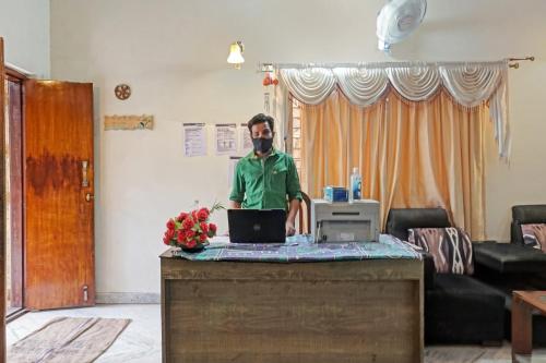 a man standing at a desk with a laptop at OYO Flagship 87488 Hotel Green Breeze in Lohogaon