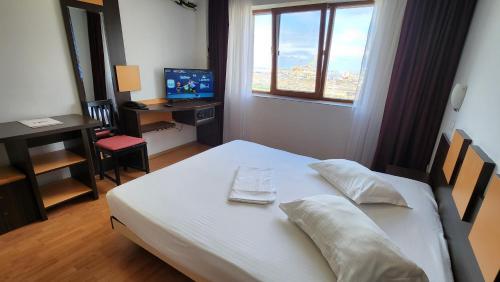 Schlafzimmer mit einem Bett und einem Schreibtisch mit einem Computer in der Unterkunft Arion Hotel in Constanţa