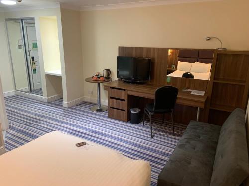 Habitación de hotel con cama y escritorio con TV. en Holiday Inn Milton Keynes East M1 Junc 14, an IHG Hotel en Milton Keynes