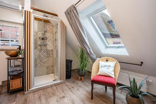 a bathroom with a shower and a chair and a window at Fachwerk in Neustadt an der Weinstraße