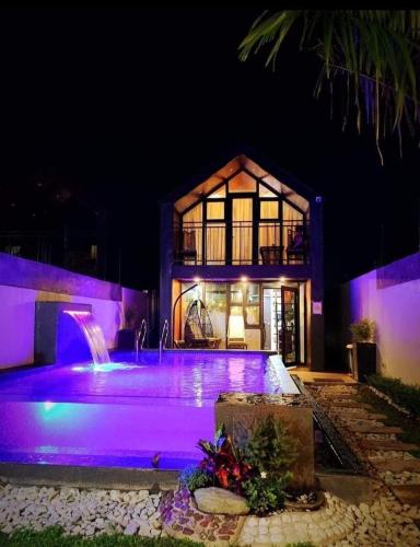 a house with purple lighting in front of a building at Hidden Haven Subic Villa w/ Infinity Pool in Subic