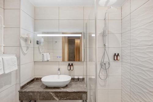 a white bathroom with a sink and a shower at Movenpick Resort and Spa Fruske Terme in Vrdnik