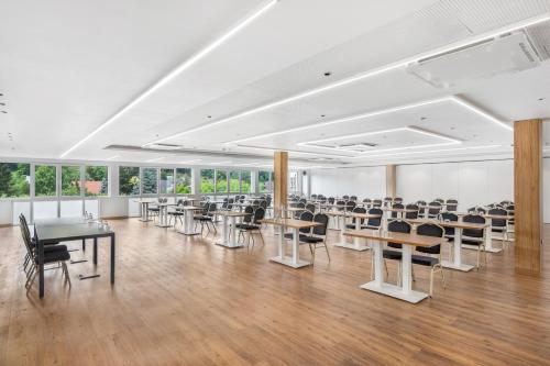 a large room with tables and chairs and windows at Movenpick Resort and Spa Fruske Terme in Vrdnik