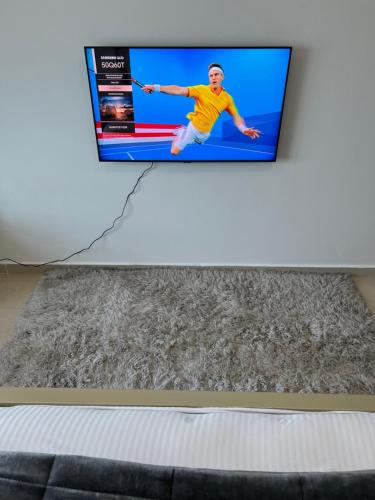 a flat screen tv hanging on a white wall at F30,R3,Sunrise on the beach,1room inside 3bedroom apartment,(separate washroom outside) in Ajman 