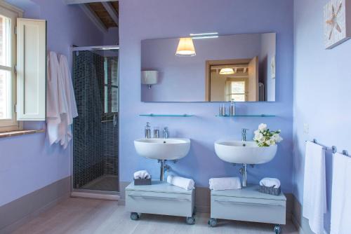a blue bathroom with a sink and a mirror at Rosa Dei Venti 8, Emma Villas in Fabro