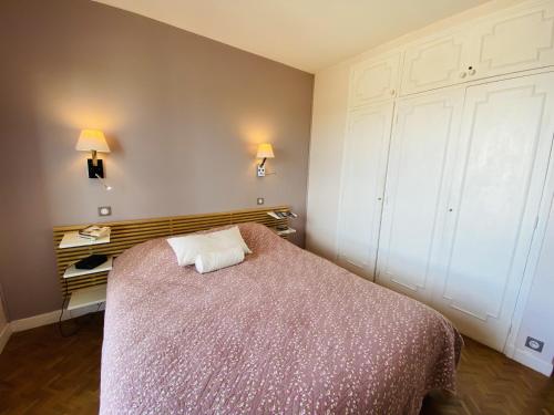 - une chambre avec un lit, une commode et deux lumières dans l'établissement Le Belle Isle, à Rodez