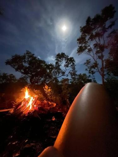 a person sitting next to a camp fire at night at Casa Porto do Sol Vila de São Jorge in Sao Jorge