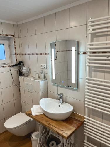 a bathroom with a sink and a toilet and a mirror at Ferienwohnung Alida in Niebüll