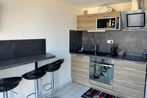 - une cuisine avec un comptoir et deux tabourets dans l'établissement T2 with swimming pool and sea accessair cooled, à Frontignan