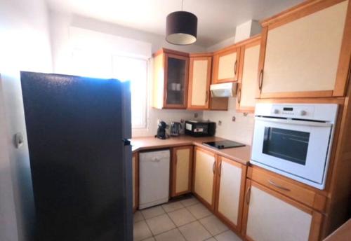 une cuisine avec un réfrigérateur noir et des armoires en bois dans l'établissement Logement entier, à Savigny-sur-Orge