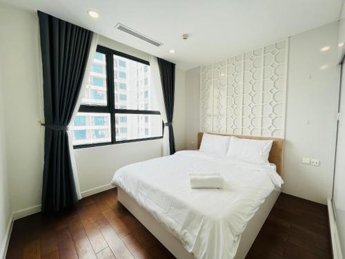 a bedroom with a white bed and a large window at Gem Apartment - VinCom D'Capitale Ha Noi in Hanoi