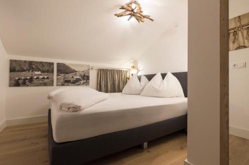 a bedroom with a bed with white sheets and pillows at Aparthotel Herzblick GmbH in See