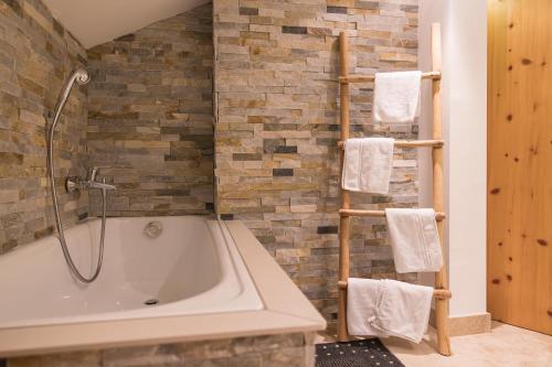 a bathroom with a tub and a stone wall at Aparthotel Herzblick GmbH in See