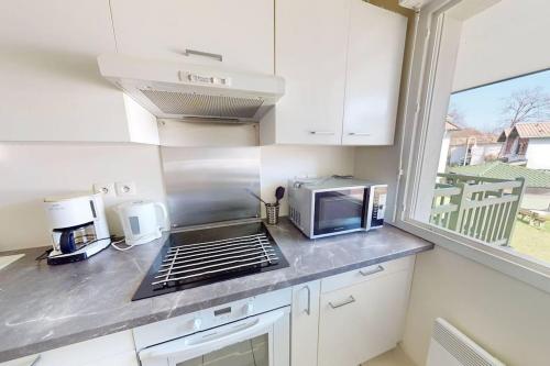 Il comprend une cuisine équipée d'une cuisinière. - un four à micro-ondes dans l'établissement BERGES LANDAISES - Grand T2 avec terrasse exposée sud est, à Capbreton