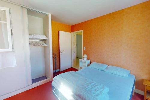 - une chambre avec un lit bleu et des murs orange dans l'établissement BERGES LANDAISES - Grand T2 avec terrasse exposée sud est, à Capbreton