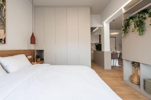 Cet appartement comprend une chambre avec un grand lit blanc et une cuisine. dans l'établissement Glamorous 4th FL Apt in Kolonaki 6 min to Syntagma, à Athènes