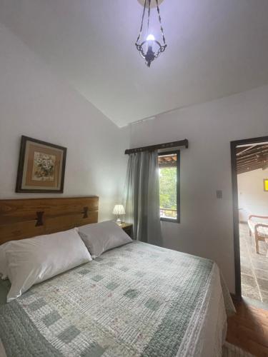 a bedroom with a bed and a window and a chandelier at Pousada das Artes in Tiradentes