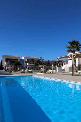 une grande piscine bleue devant une maison dans l'établissement Résidence La Dolce Vita, à Ghisonaccia