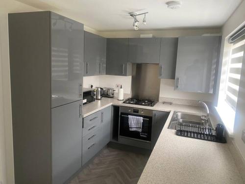 a kitchen with white cabinets and a stove and a sink at Brand New 3 Bedrooms Detached House in Westhoughton