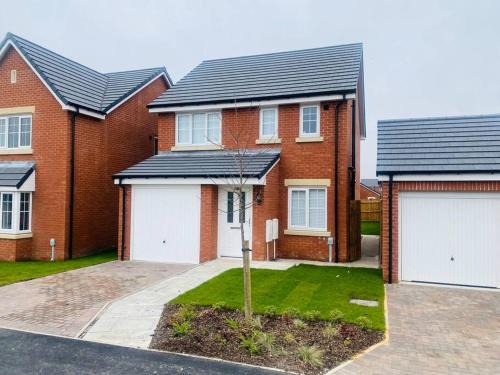 a red brick house with two white garage doors at Brand New 3 Bedrooms Detached House in Westhoughton
