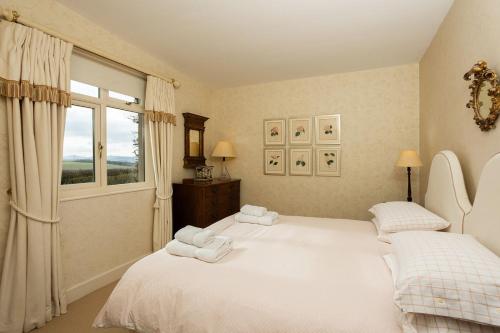 a bedroom with two beds and a window at Melkington Lodge in Cornhill-on-tweed