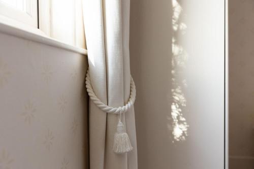 a white curtain with a tassel on a window at Melkington Lodge in Cornhill-on-tweed