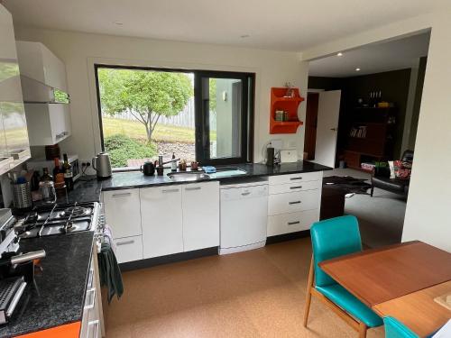 a kitchen with white cabinets and a table and a window at Lake Hawea Haven - Lake Hawea Holiday Home in Lake Hawea